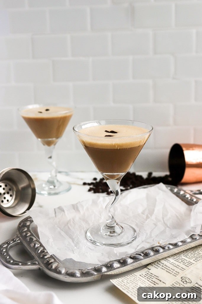 Two creamy espresso martini cocktails in martini glasses on silver serving platter