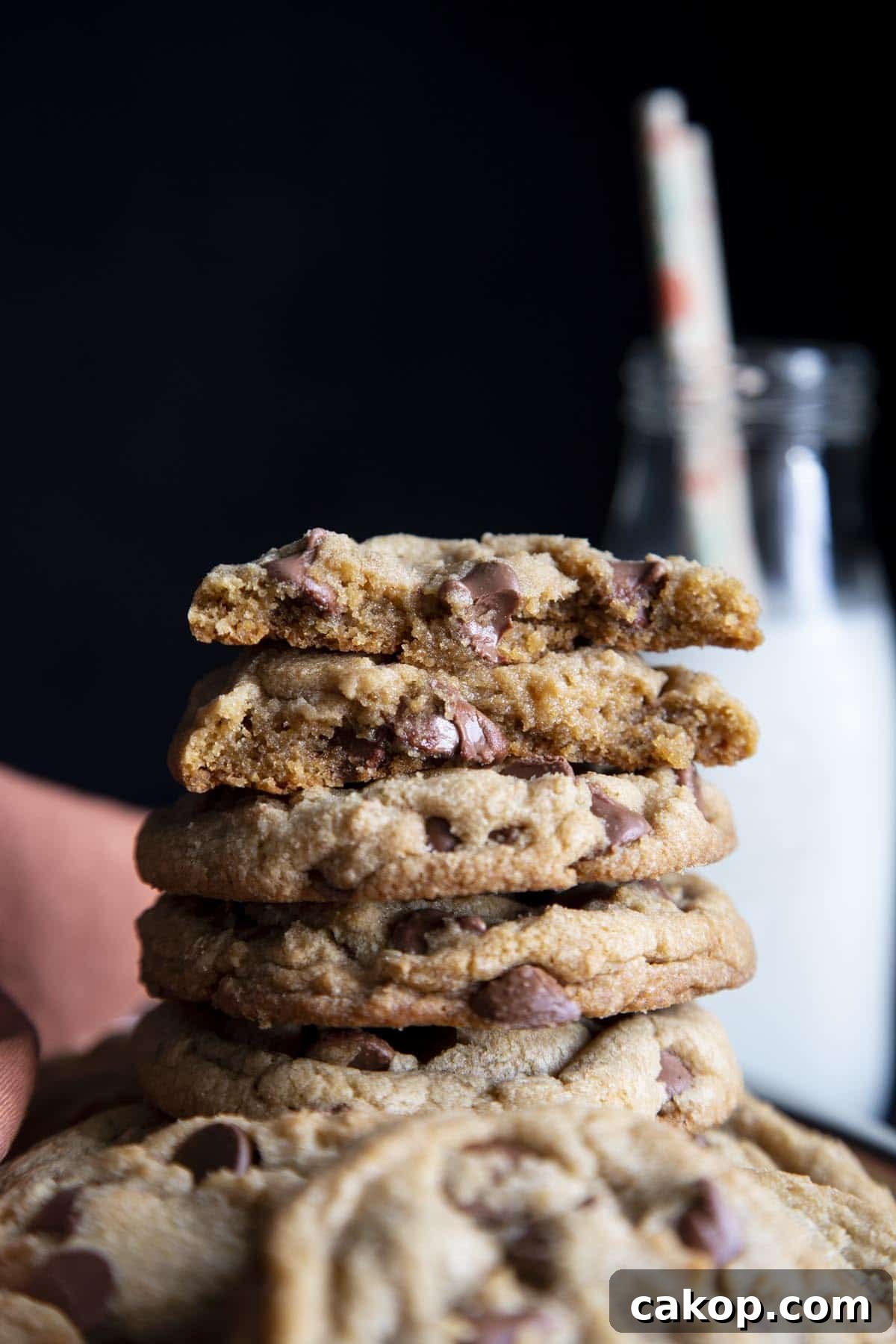 Chewy Milk Chocolate Chip Cookies Recipe for Perfect Cookies 10 A stack of chocolate chip cookies with the top one broken in half showing melted chocolate chip.