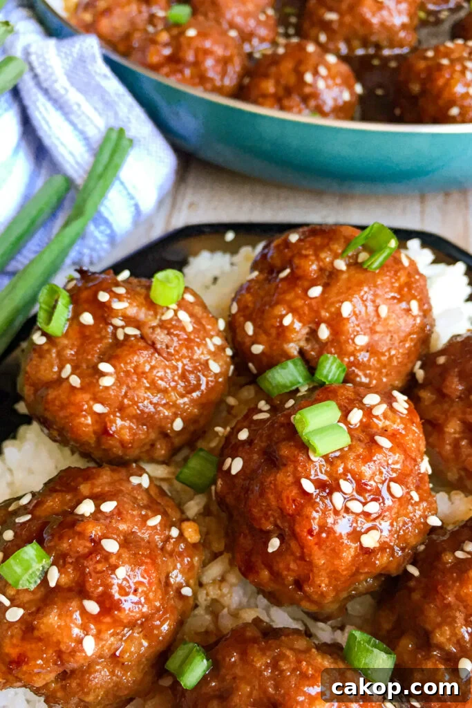Sticky Asian Glazed Meatballs Recipe: Sweet-Savory Sauce Guide 2 Asian Glazed Meatballs with white rice, sesame seeds, and green onions for garnish. Skillet with meatballs in the background
