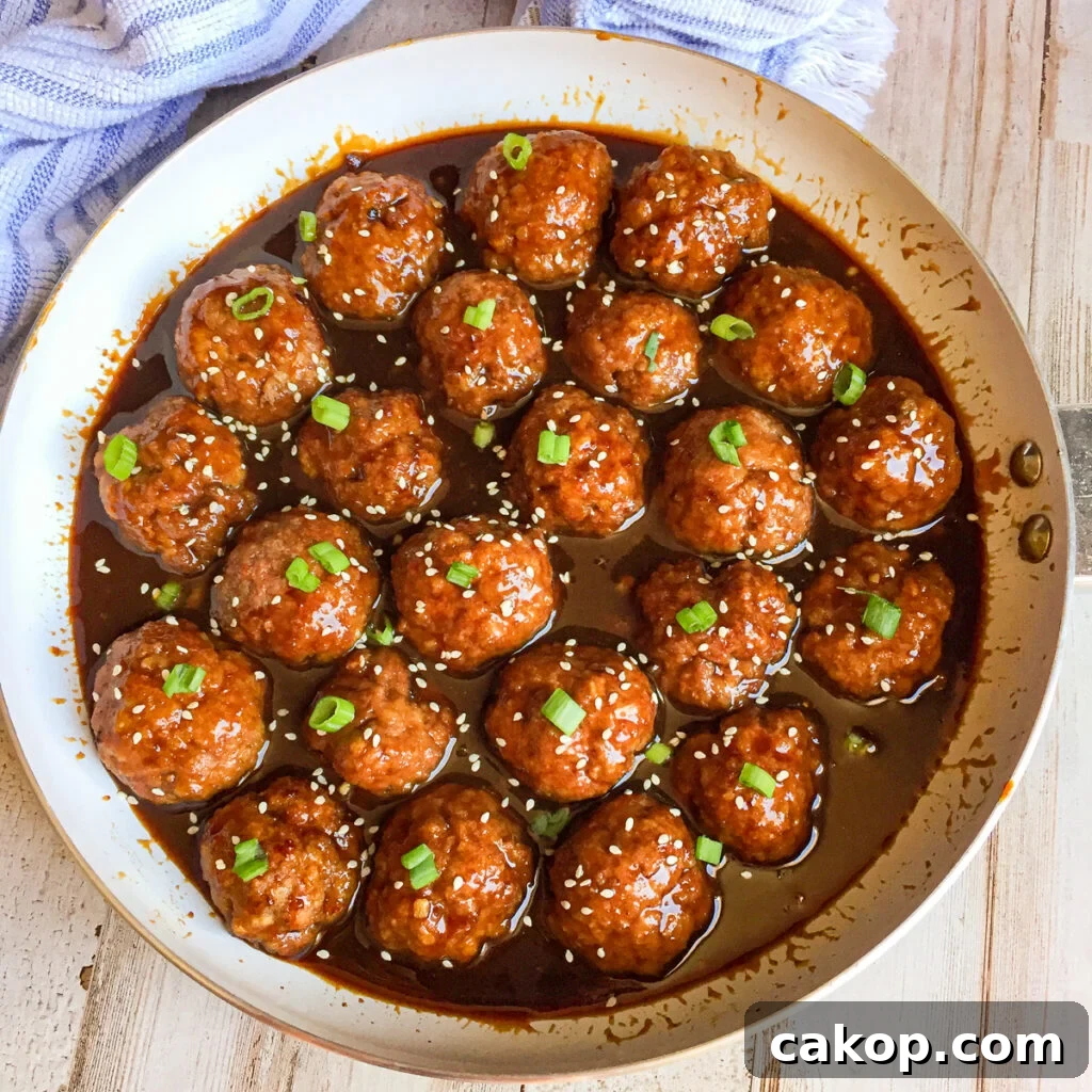 Sticky Asian Glazed Meatballs Recipe: Sweet-Savory Sauce Guide 3 Asian glazed meatballs in a white skillet with sesame seeds and chopped green onions for a garnish