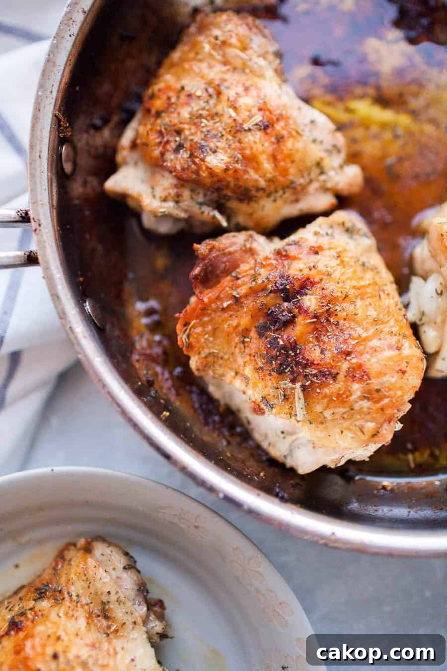 chicken thighs cooking in a stainless steel plan