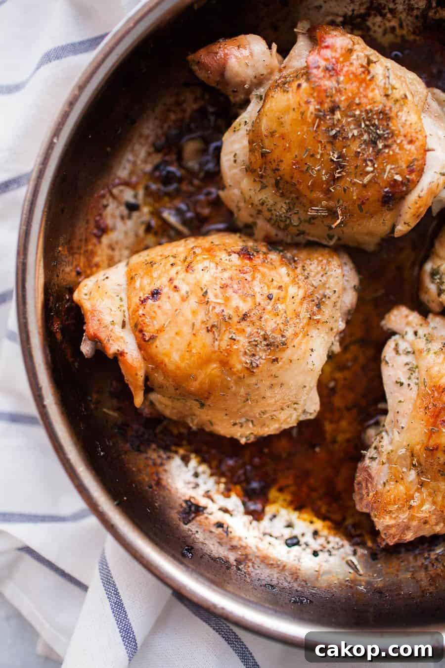 Pan-seared chicken thighs in a stainless steel dish. 