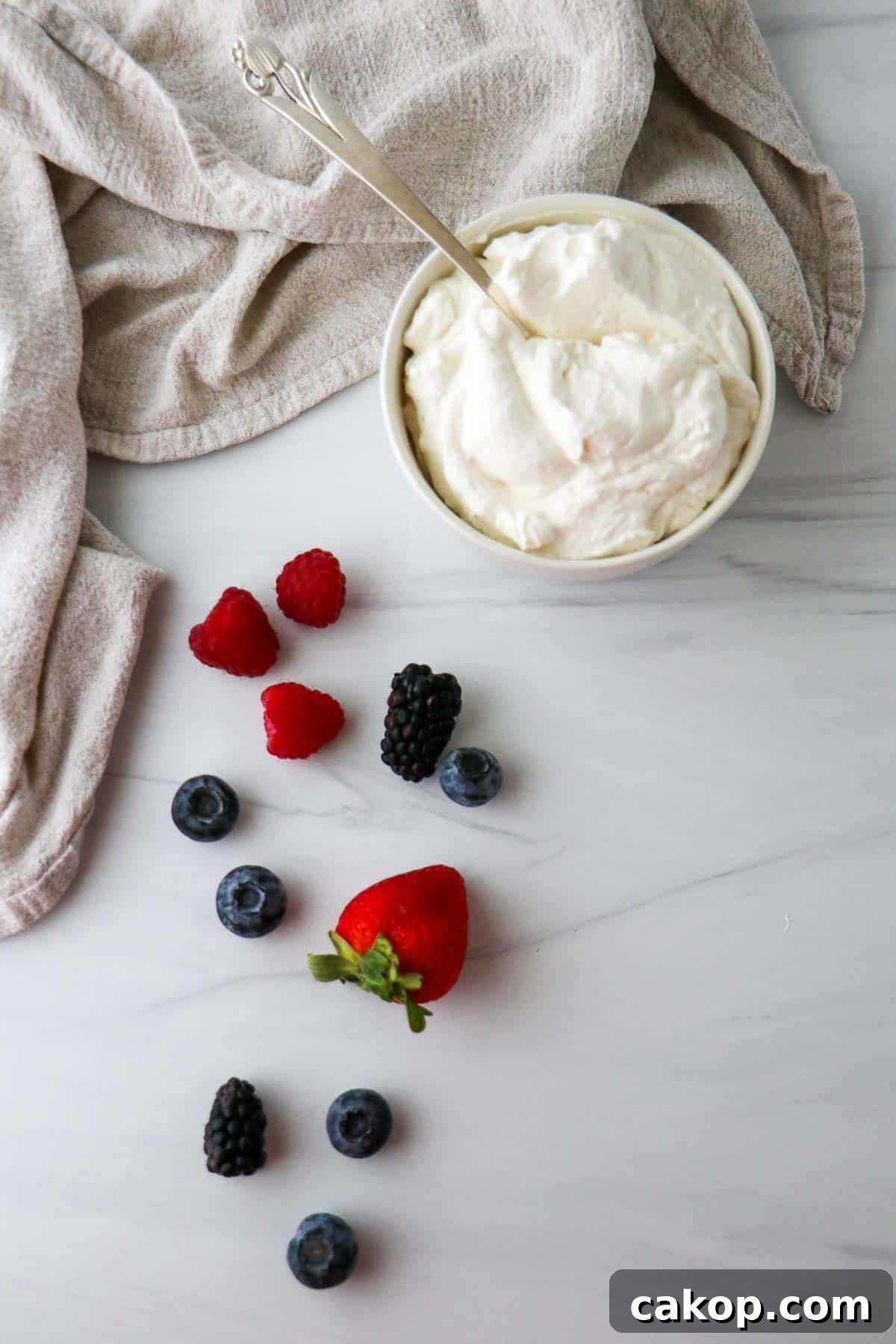 Light Scandinavian Elderflower Cream Dessert for Summer 2 Elderflower Cream in a bowl with a spoon next to fresh mixed berries.