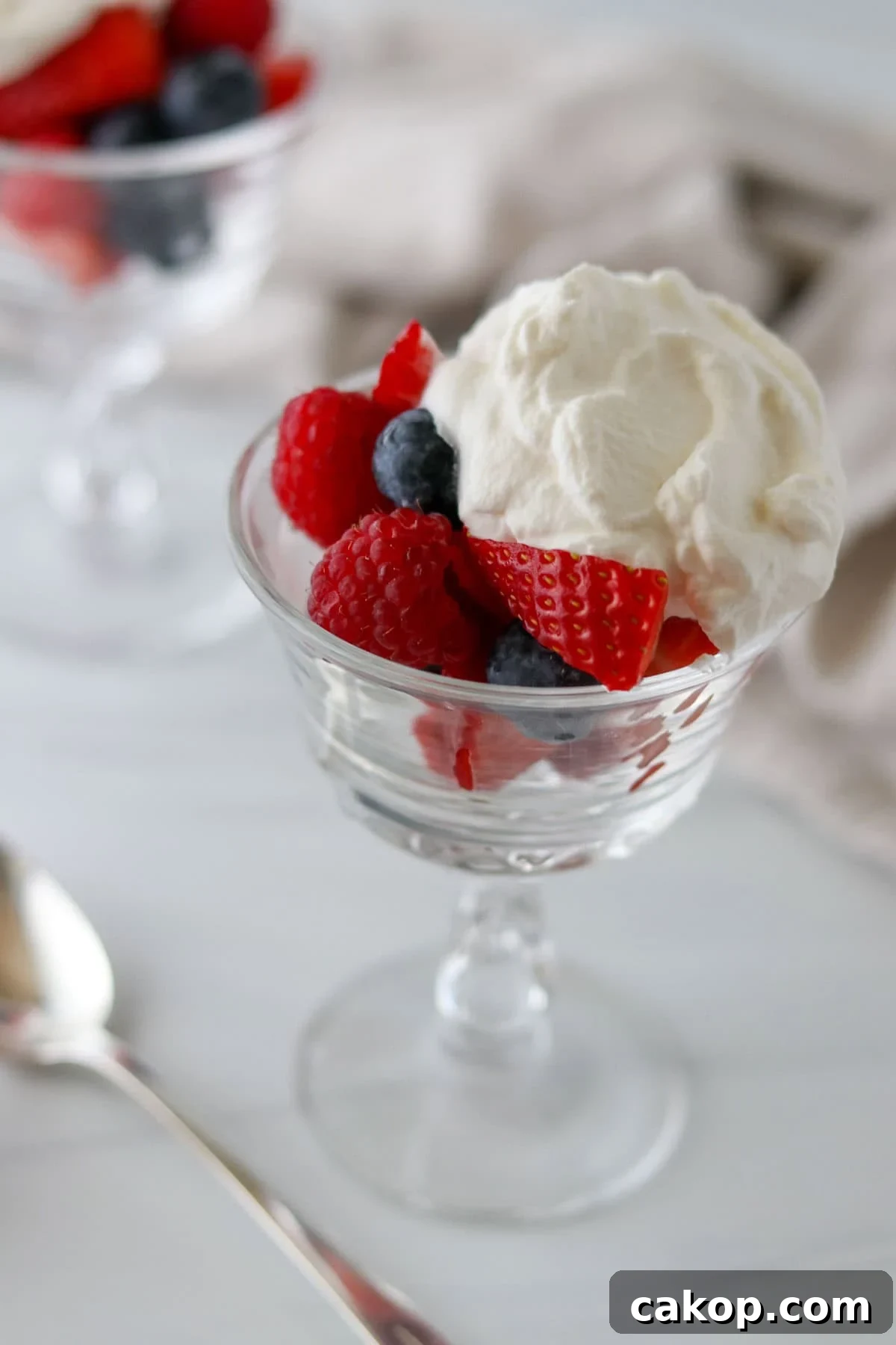 Light Scandinavian Elderflower Cream Dessert for Summer 5 Elderflower Cream over berries in a stemmed glass.