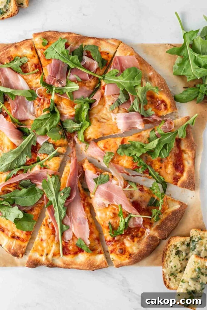 A prosciutto pizza cut into slices with rocket.