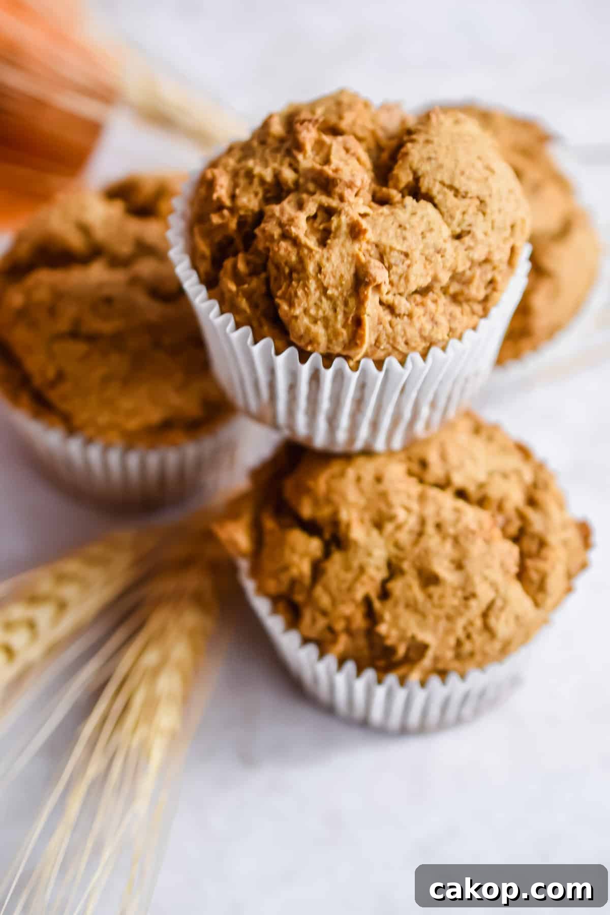 2-Ingredient Pumpkin Spice Muffins — Quick Autumn Recipe 2 Four muffins are stacked with a piece of wheat underneath the pyramid.