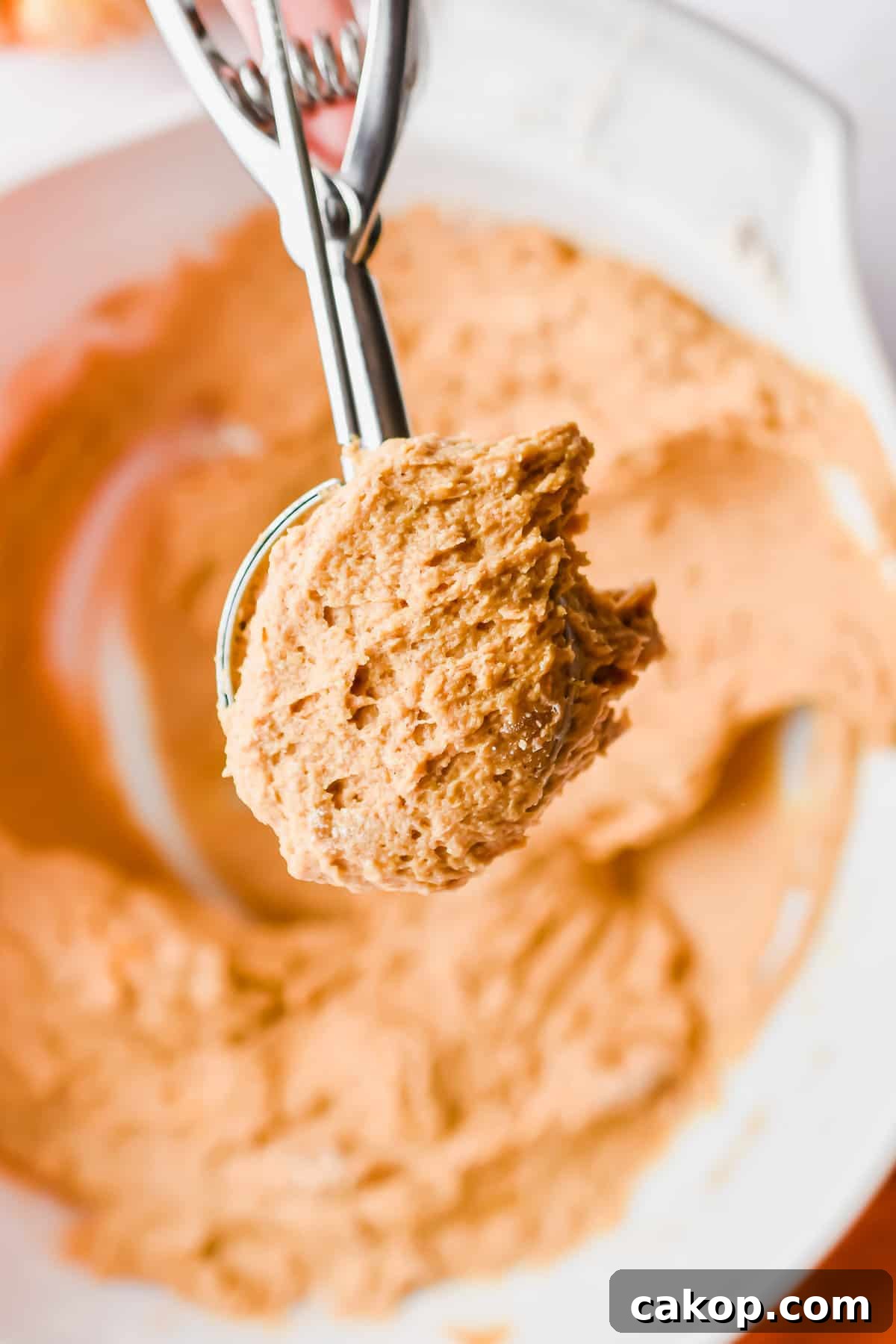 2-Ingredient Pumpkin Spice Muffins — Quick Autumn Recipe 6 An ice cream scoop is scooping out the pumpkin muffin batter.