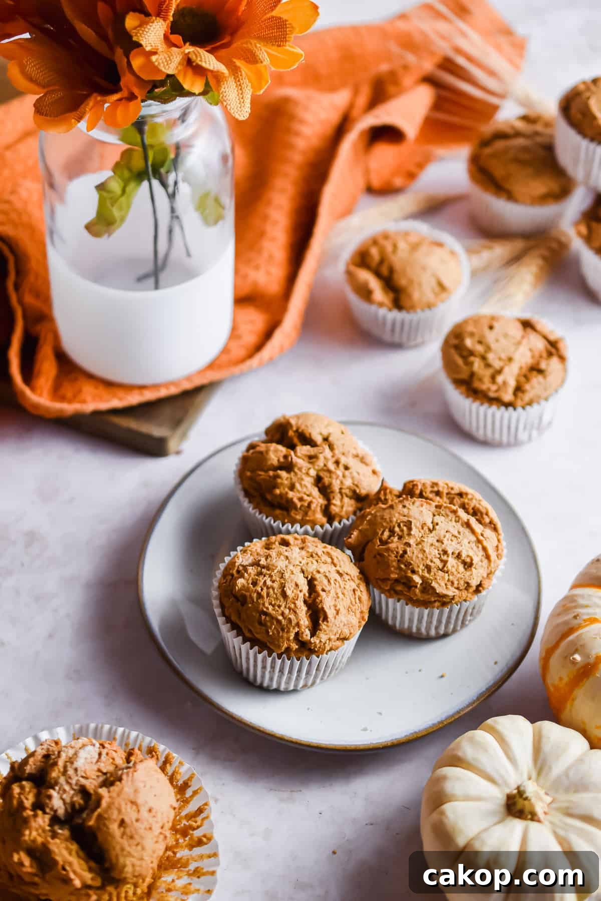 2-Ingredient Pumpkin Spice Muffins — Quick Autumn Recipe 8 A table scape of muffins, pumpkins, and flowers.
