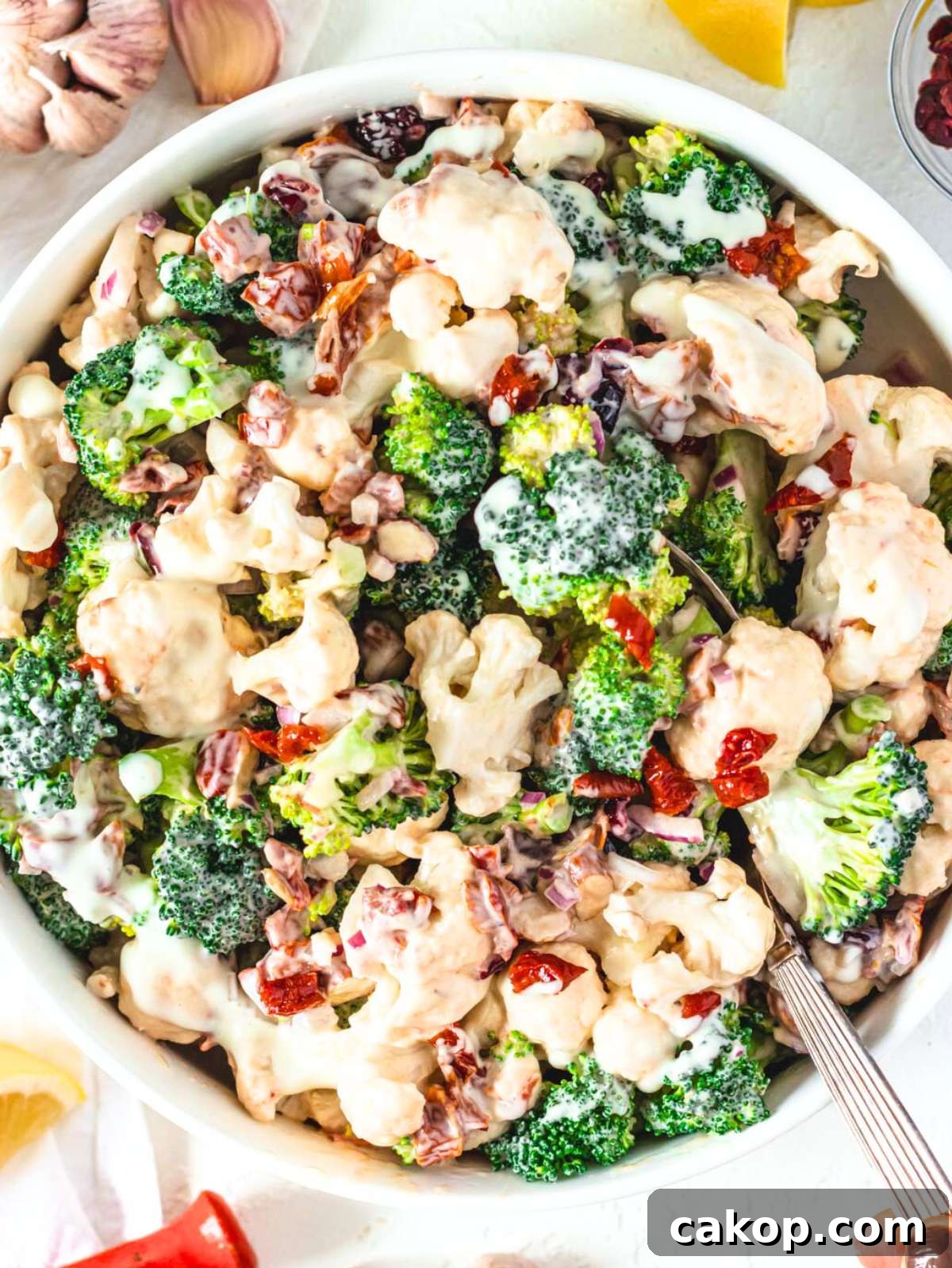 Overhead view of creamy healthy broccoli cauliflower salad with sun dried tomatoes and cranberries.