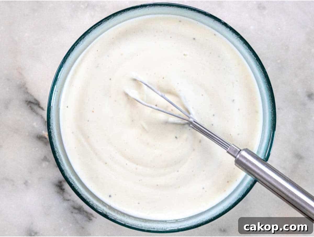 Step 2 Whisking Greek yogurt dressing with vinegar mustard and honey for creamy broccoli cauliflower salad.