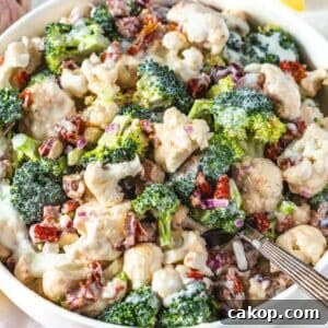 Fresh healthy broccoli cauliflower salad with Greek yogurt dressing served in a bowl with silver spoon.