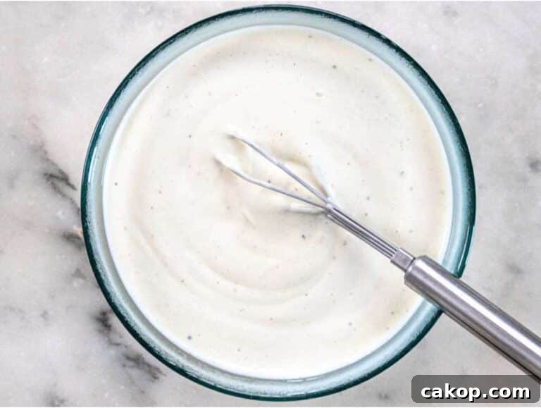 Step 2 Whisking Greek yogurt dressing with vinegar mustard and honey for creamy broccoli cauliflower salad.