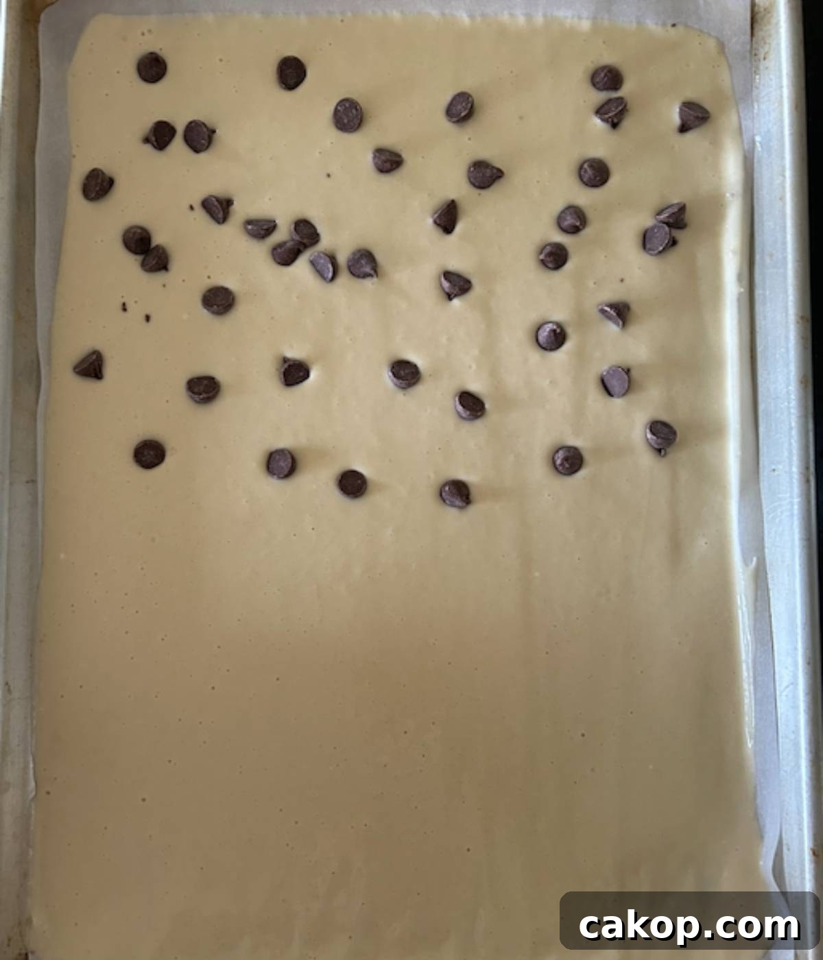 Sheet-Pan Pancakes from Mix (Oven-Baked) 8 Pancake batter in sheet pan, half topped with chocolate chips.