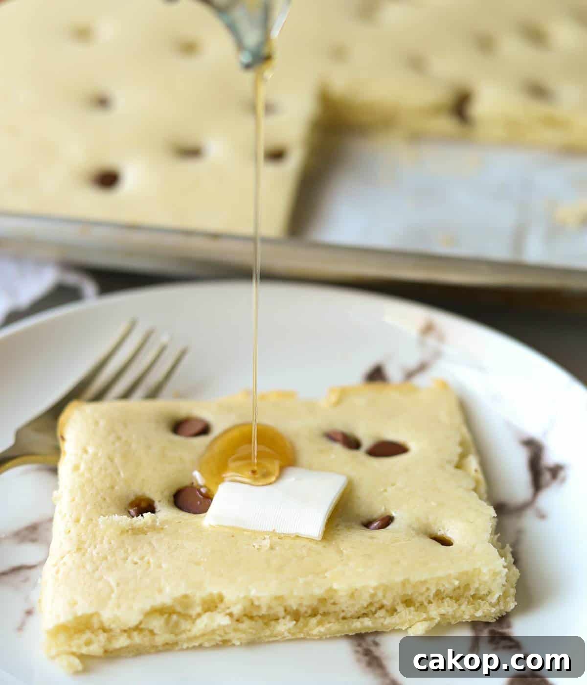 Sheet-Pan Pancakes from Mix (Oven-Baked) 9 Pancake square with butter and syrup pouring over the top.