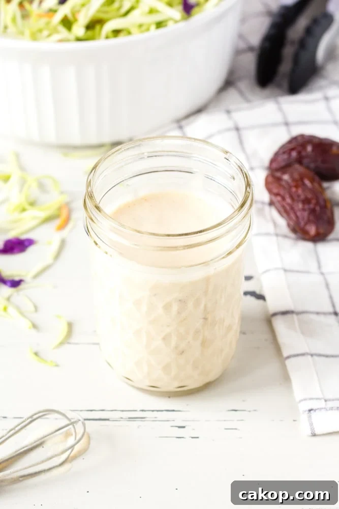 What to Serve with Coleslaw: 25+ Delicious Meal Ideas 3 creamy homemade coleslaw dressing in a small mason jar next to a bowl with slaw in it.