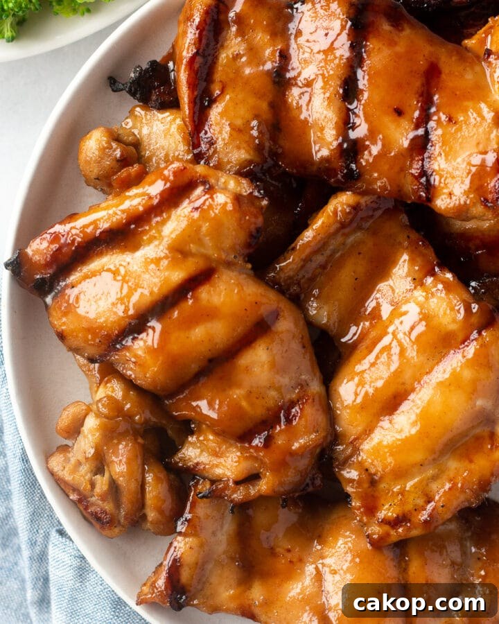What to Serve with Coleslaw: 25+ Delicious Meal Ideas 9 top down shot of gluten free grilled chicken thighs on a white plate. A plate of broccoli is in the upper left corner and a blue cloth napkin is in the bottom left corner.