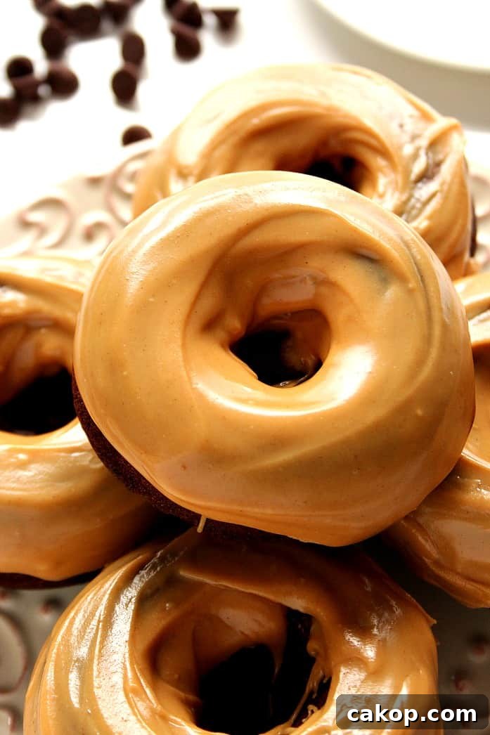Overhead shot of chocolate donuts with smooth peanut butter glazed stacked on a plate. 