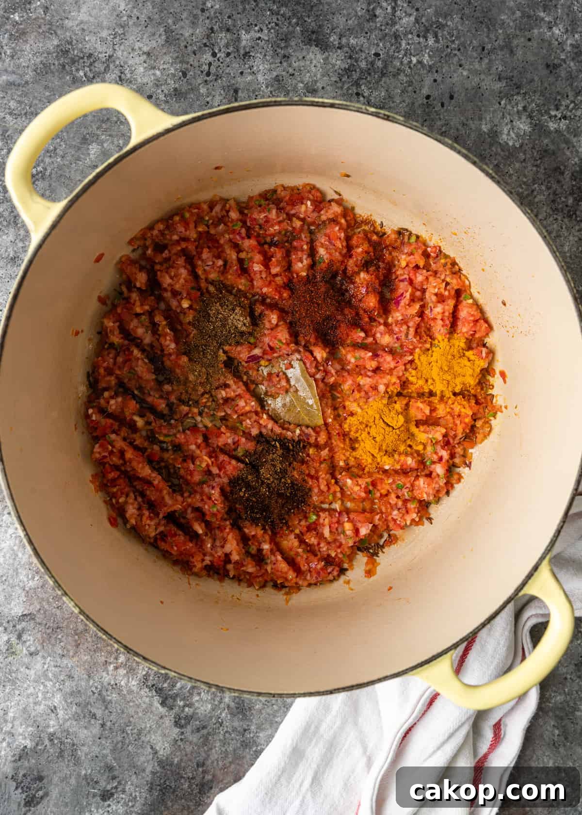 adding bay leaf to ingredients in pan