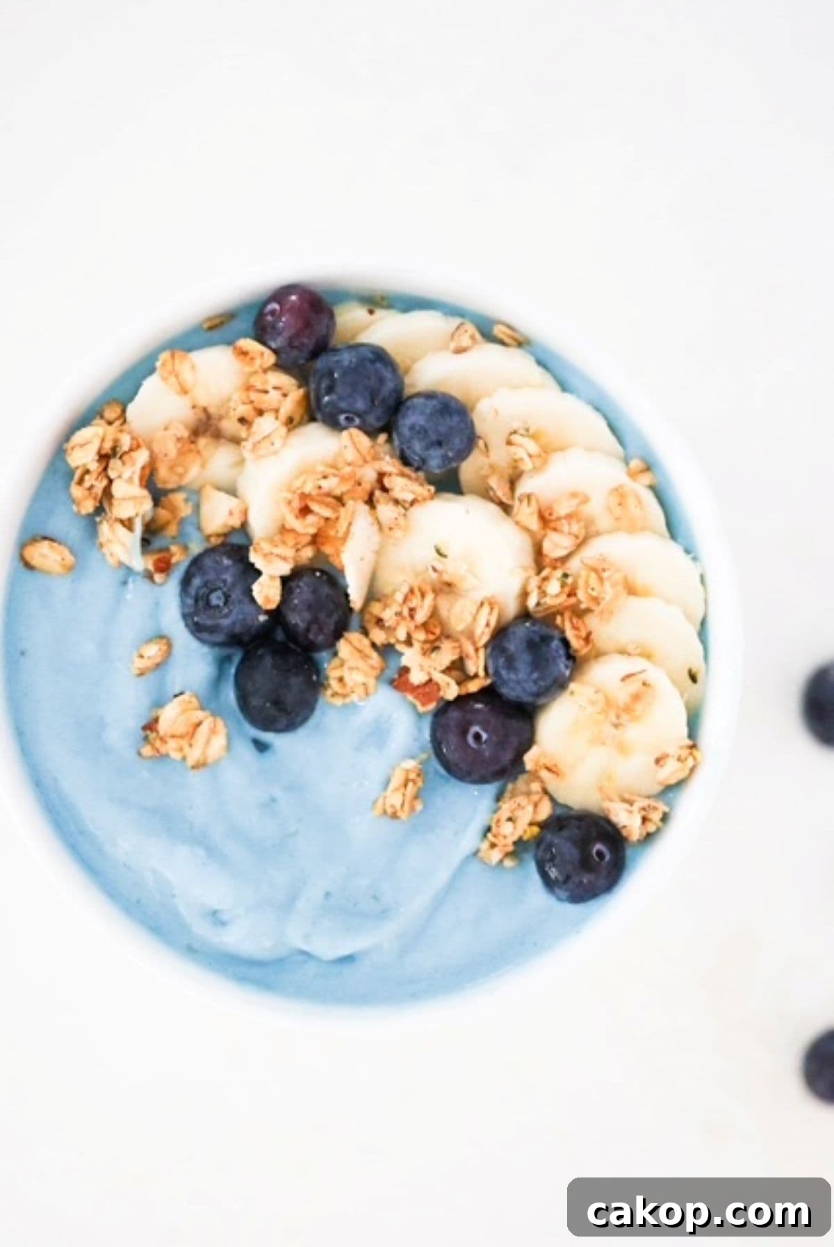Blue Spirulina Smoothie Bowl Recipe for Instagram-Worthy Breakfast 2 Blue smoothie bowl topped with banana slices, blueberries, and granola.