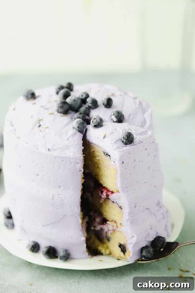 tall lavender cake on white plate with a slice being removed