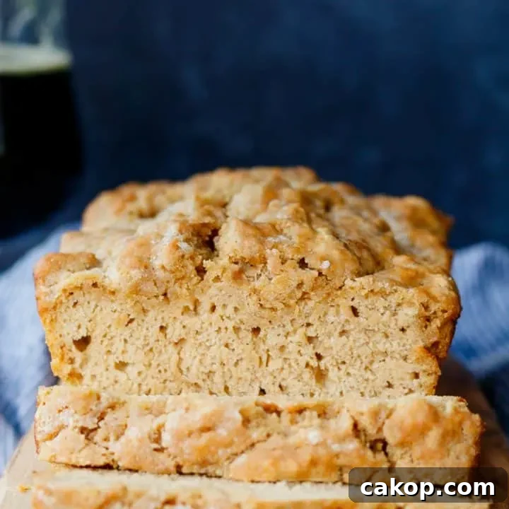 sliced beer bread on a cutting board with a glass of beer near the rear left of the photo.