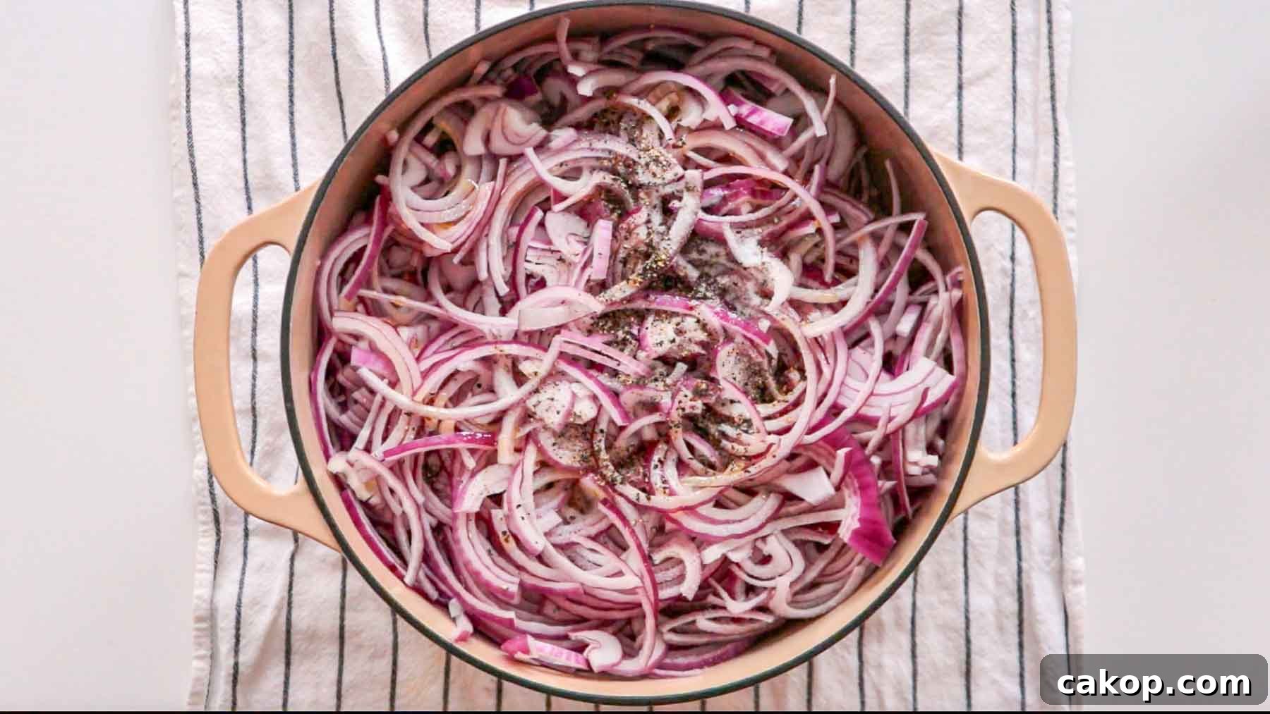 Sliced red onions and black pepper in a dutch oven.