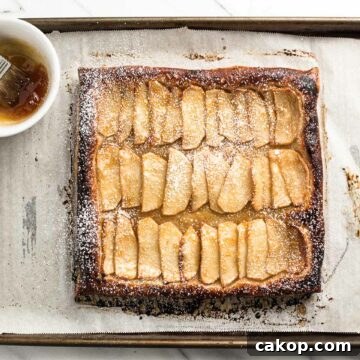How to Make a Rustic Apple Tart: Flaky Crust & Cinnamon Apples 7 apple tart on a baking sheet with apricot jam in a bowl.