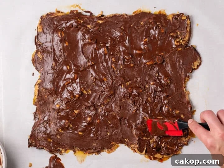 High-Protein Snickers Date Bark Recipe for Satisfying Snacks 15 Melted chocolate spread across the top of the peanut butter date bark layer