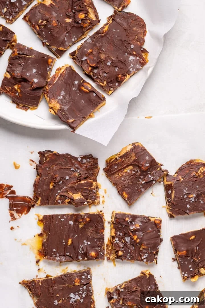 High-Protein Snickers Date Bark Recipe for Satisfying Snacks 18 Sliced pieces of snickers date bark topped with melted chocolate, peanuts, and flaky sea salt on parchment paper