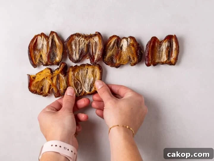 High-Protein Snickers Date Bark Recipe for Satisfying Snacks 6 Hands pressing opened dates flat on a sheet of parchment paper