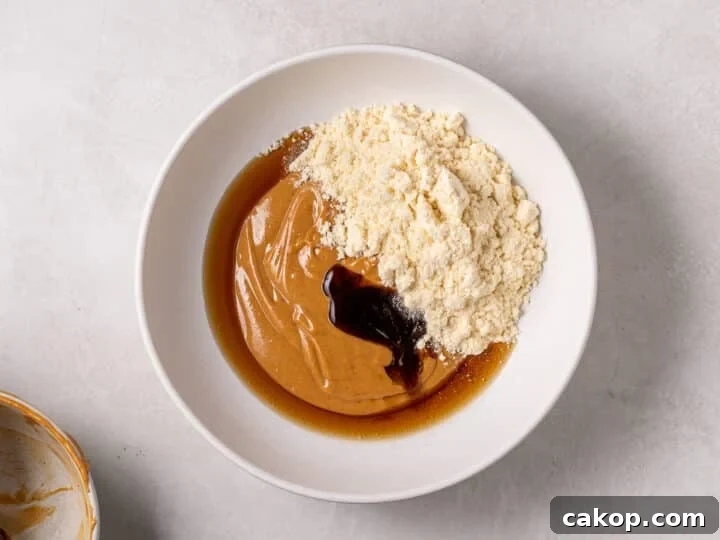 High-Protein Snickers Date Bark Recipe for Satisfying Snacks 10 Peanut butter mixture in a bowl with vanilla protein powder, maple syrup, and vanilla extract