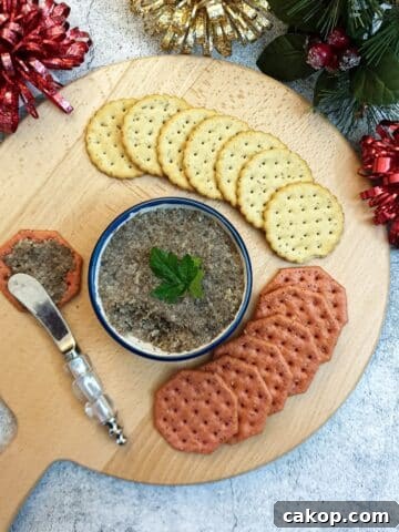 A dish of mushroom pate on a wooden board surrounded by crackers.