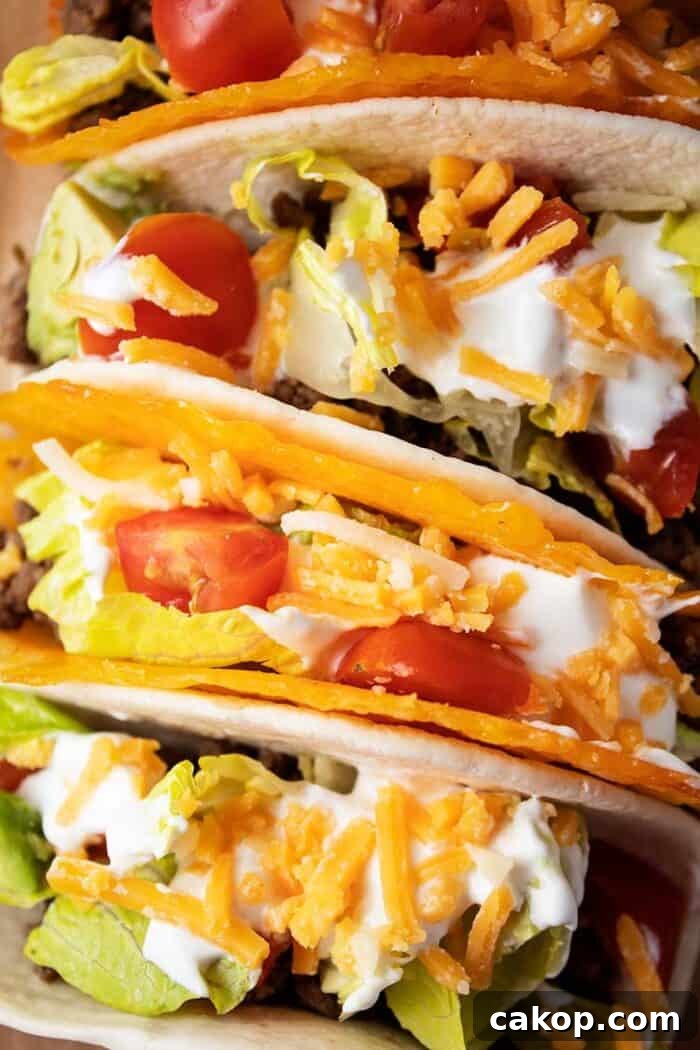 overhead view of 4 tacos with 2 in cheese shells and 2 in tortillas with meat, lettuce, tomato, cheese and avocado