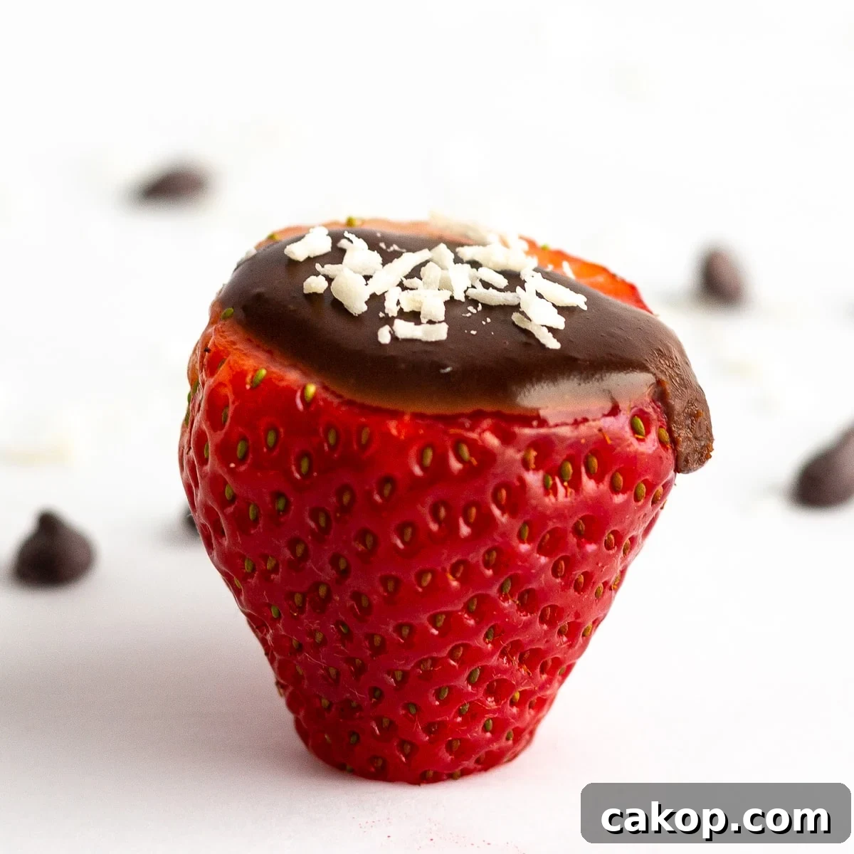 Single strawberry filled with chocolate coconut cream and a few flakes of shredded coconut scattered on the top.