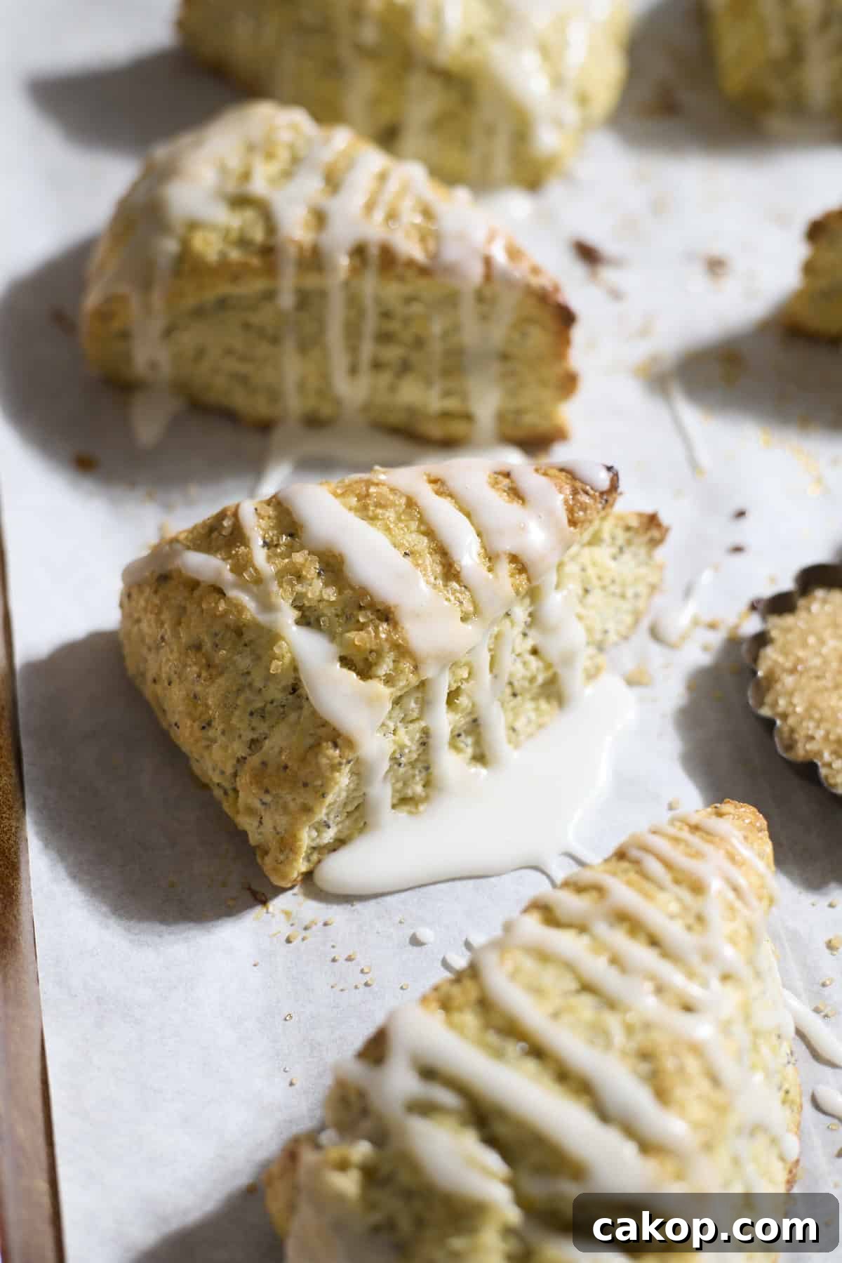 Sourdough Lemon Poppy Seed Scones Recipe for Tender, Tangy Bakes 2 Sourdough Lemon Poppy Seed Scones on white parchment paper.