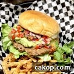 Guacamole Burger Recipe: Juicy Beef Patties with Fresh Avocado 7 Burger with guacamole and pico de gallo on checked paper with crispy onions.