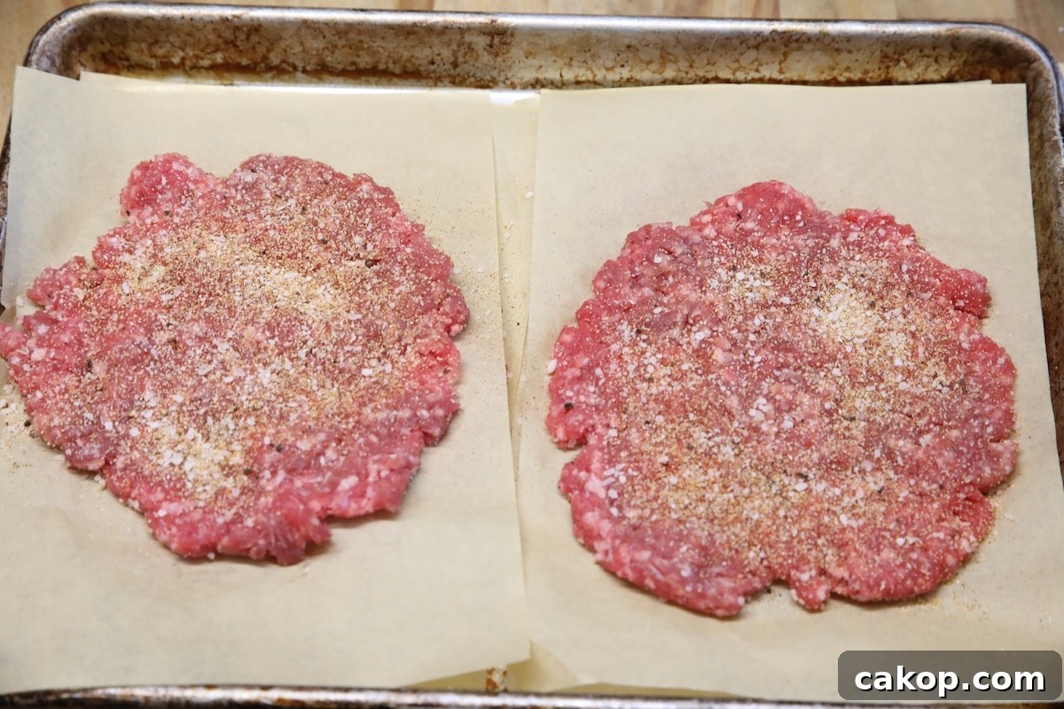 Blackstone smash burgers recipe. Seasoned ground beef patties on parchment.