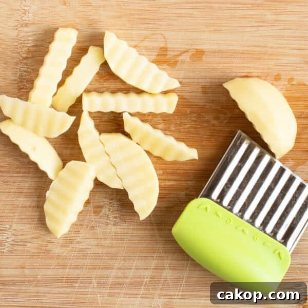 Cutting potatoes into chips on a chopping board.
