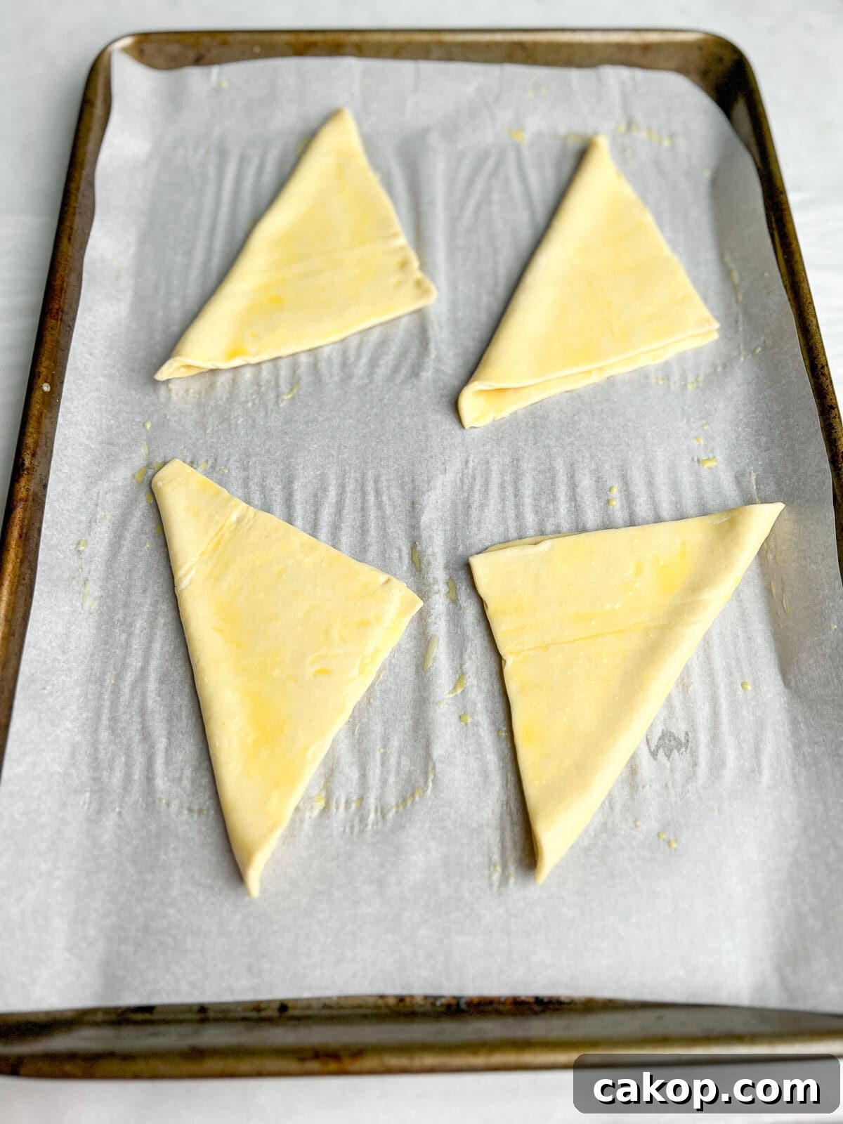 Strawberry Cheesecake Turnover Recipe — Flaky Pastry with Creamy Filling 8 puff pastry folded into triangles on a pan