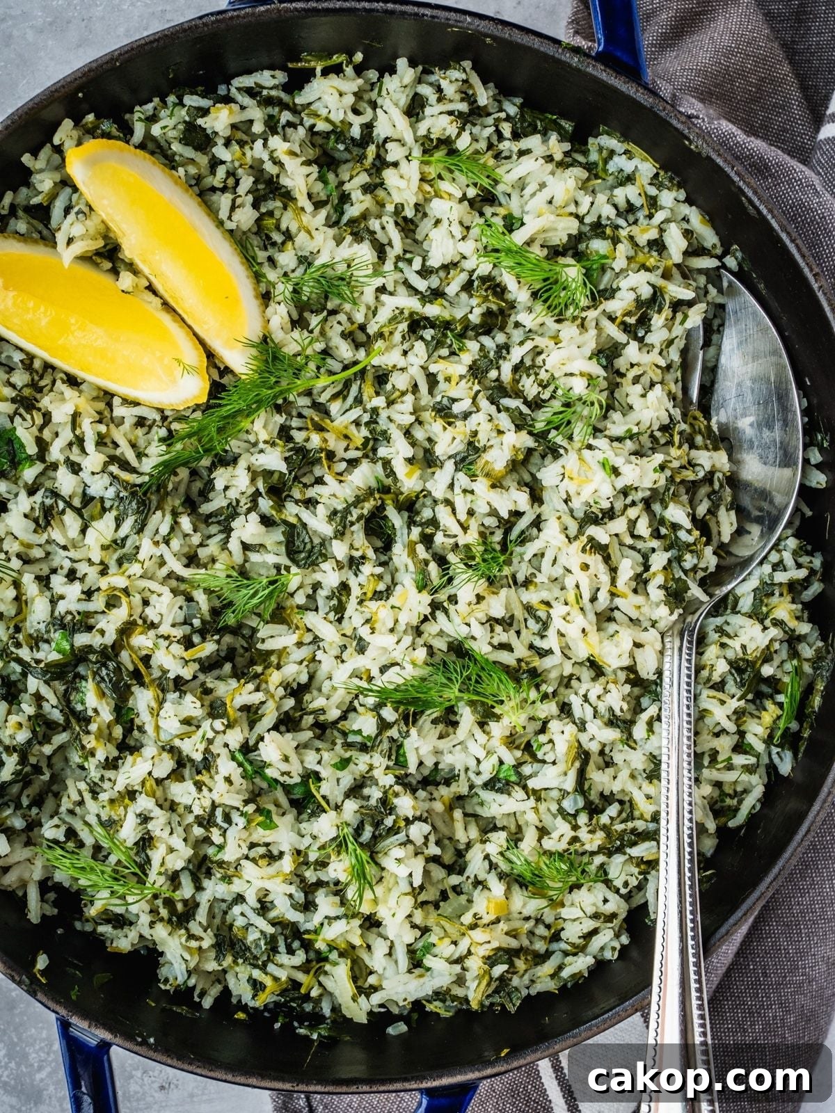 Spanakorizo Greek Rice with spinach in a large pot, garnished with lemon wedges and extra fresh dill.