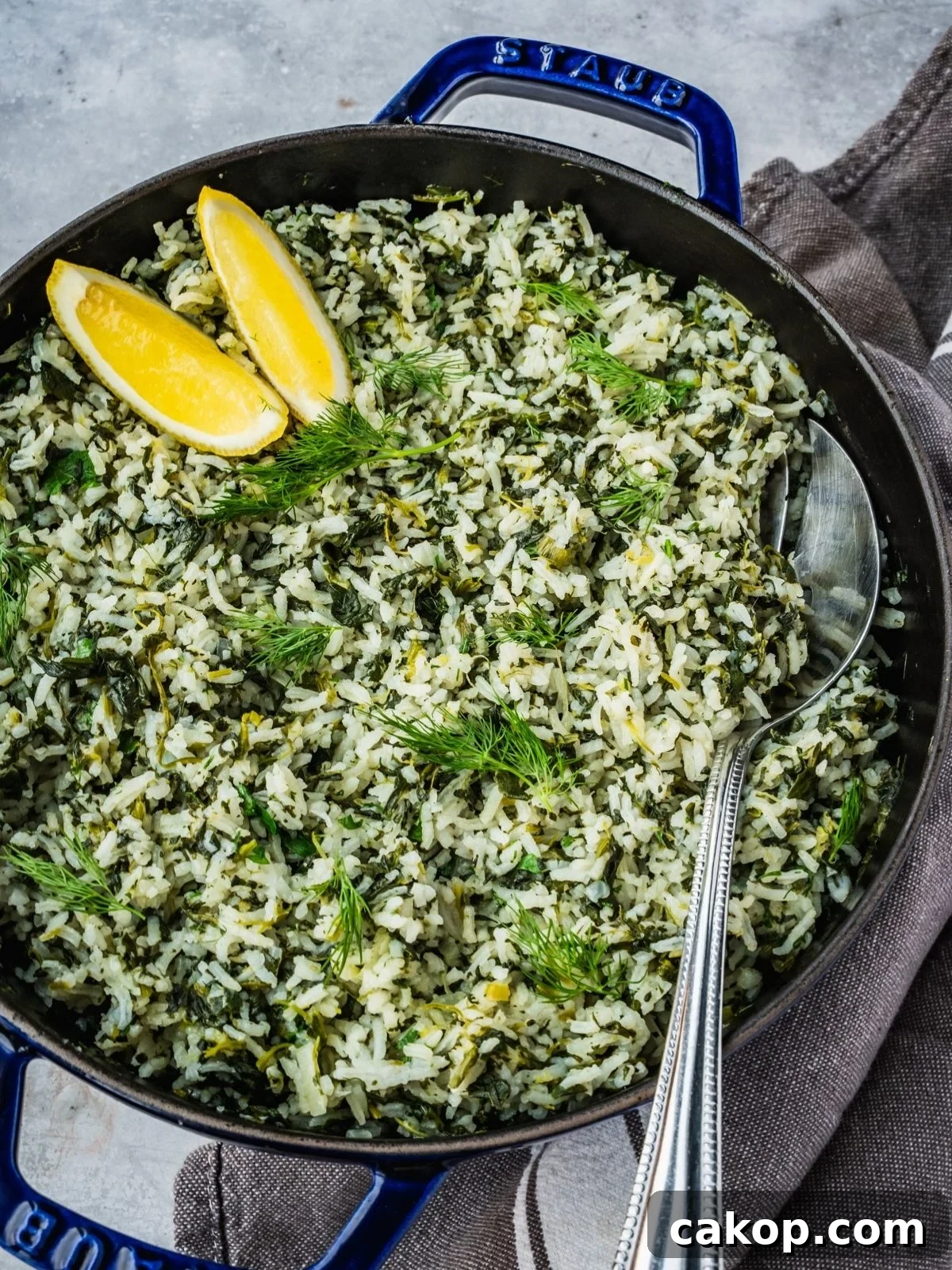 Spanakorizo Greek Rice with spinach in a large pot, garnished with lemon wedges and extra fresh dill.