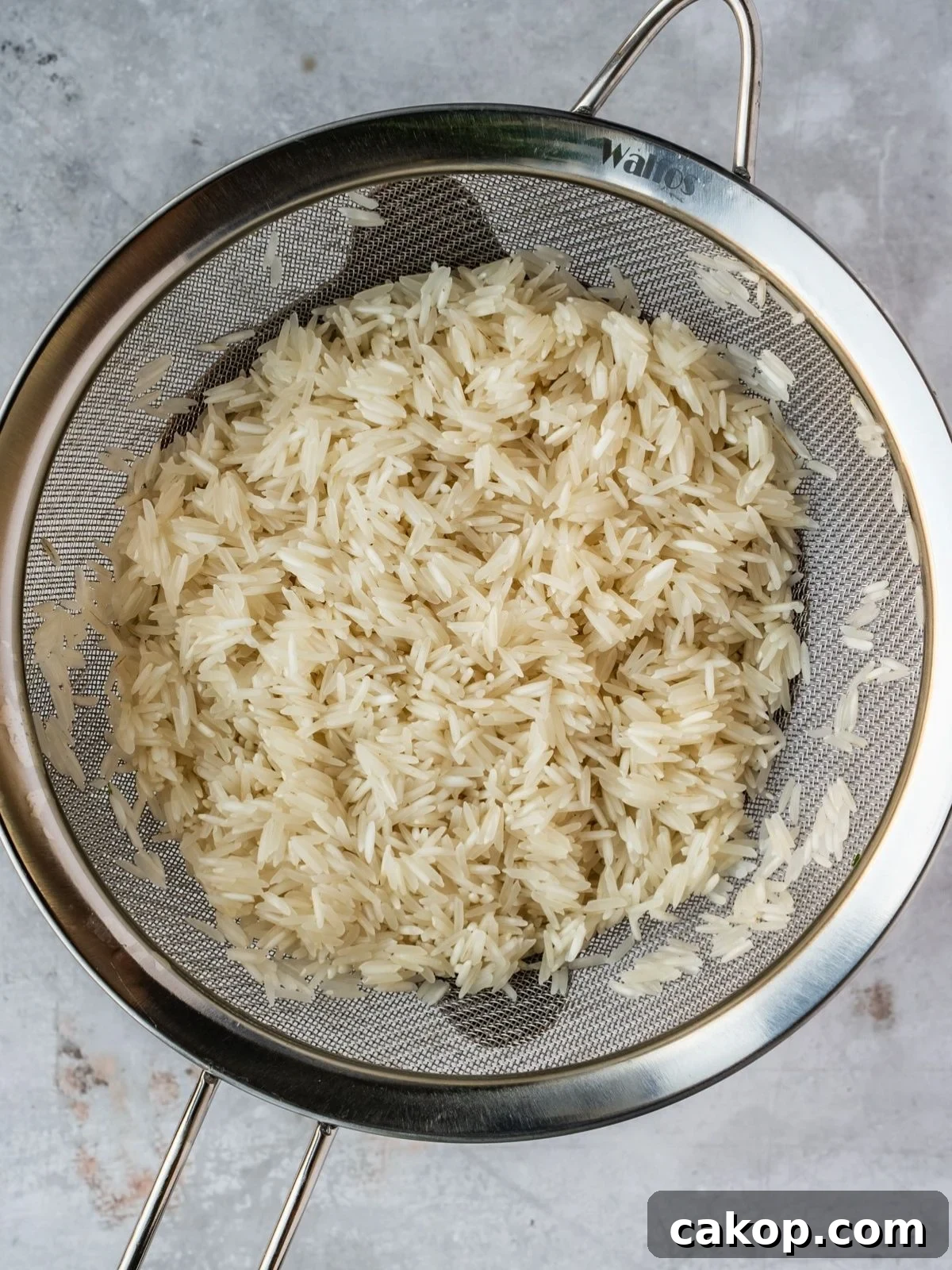 Rinsed rice draining in a small metal sieve.
