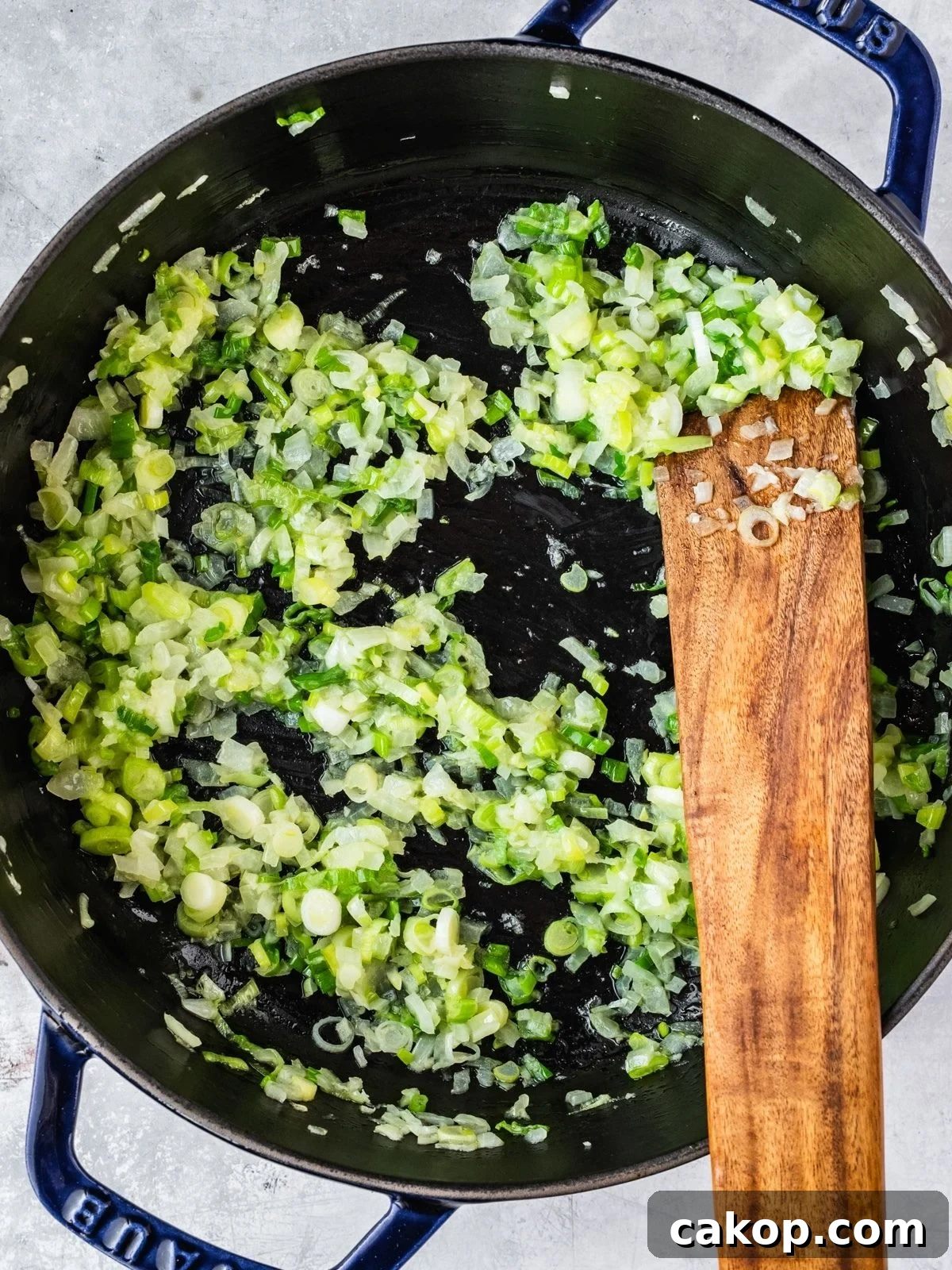 Diced onion and green onion frying in a pot.