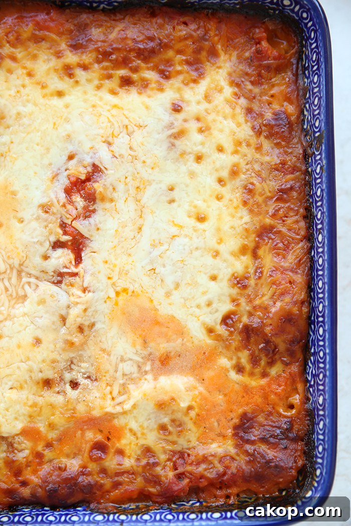 A partial vertical picture of a large dark blue rectangular Polish pottery baking dish of red pepper lasagna.