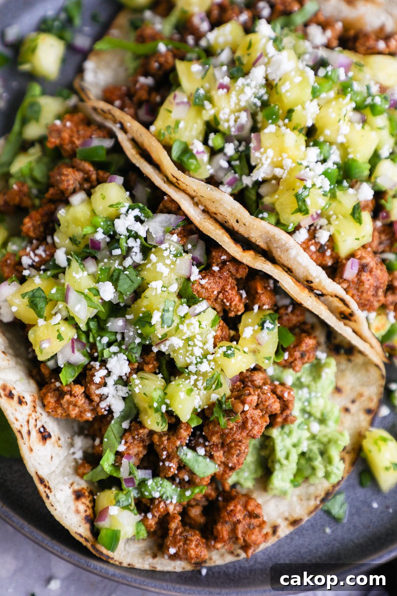 Pork tacos made with ground pork al pastor, pineapple salsa, mashed avocado and a sprinkle of cotija cheese