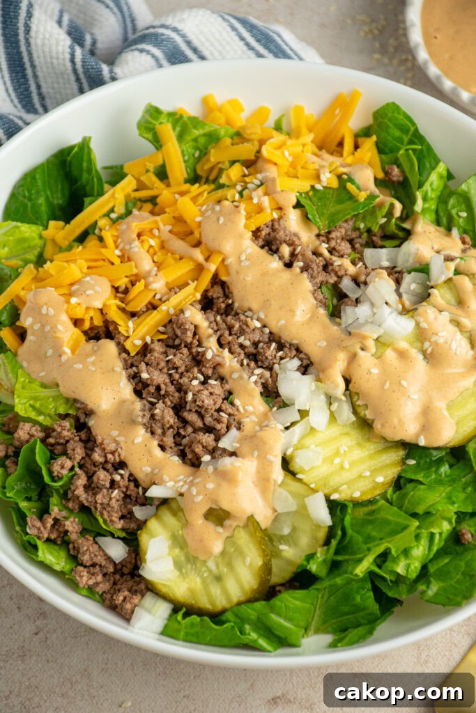 Close up of a big mac salad in a white serving bowl with big mac sauce on top.