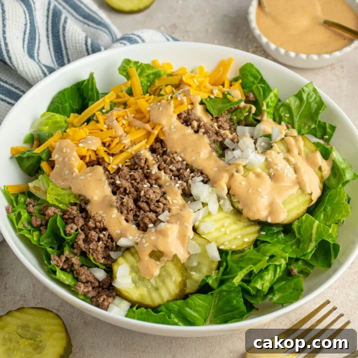 A white bowl filled with big mac salad with ground beef, pickles, cheese, and special sauce.