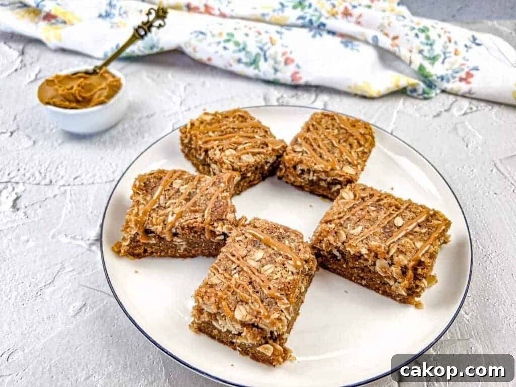A white plate with five biscoff cookie butter streusel bars, each drizzled with melted cookie butter.