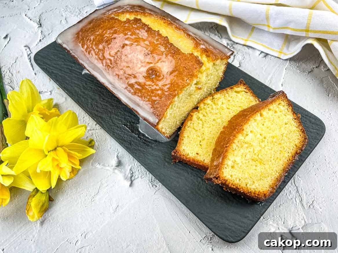 A slice of lemon pound loaf on a plate with daffodils.