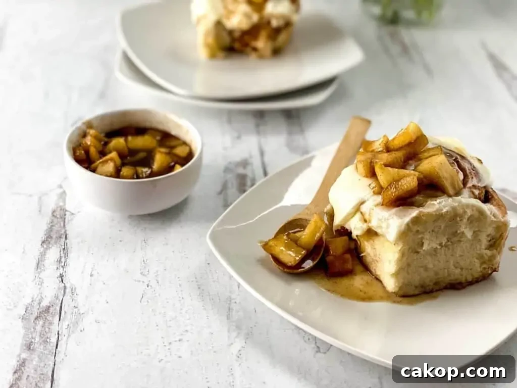 An apple cinnamon roll on a plate with a spoon.